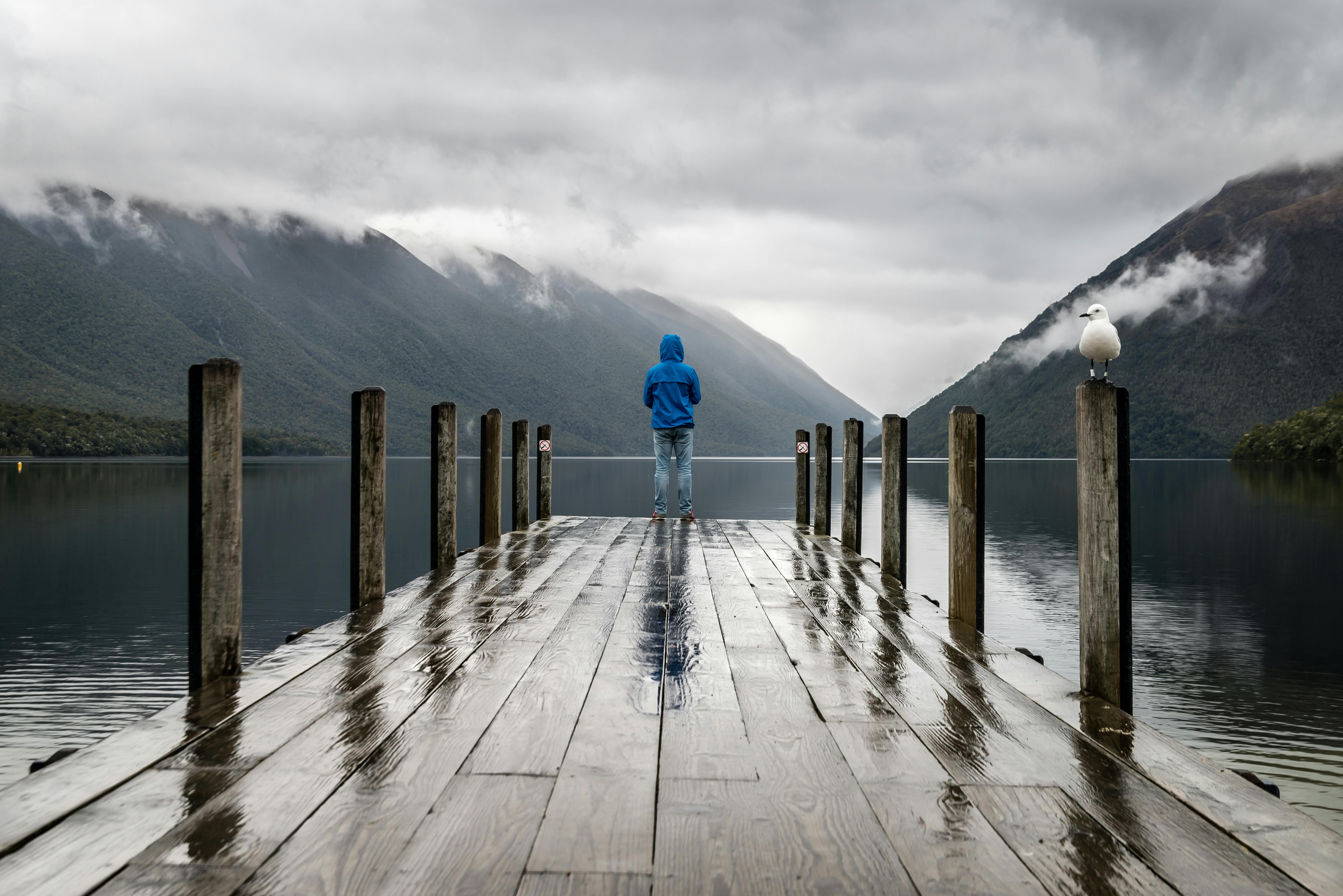 Man standing at end of dock over a lake